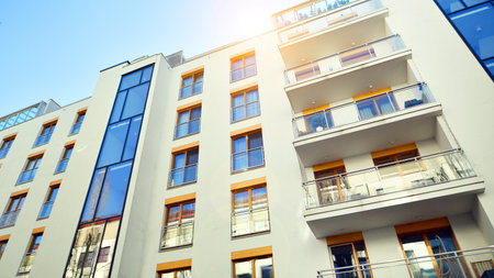 Apartment building with symmetrical modern architecture in the city. Modern apartment building on a sunny day. Facade of a modern apartment building. Bottom view.の写真素材