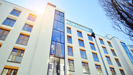 Apartment building with symmetrical modern architecture in the city. Modern apartment building on a sunny day. Facade of a modern apartment building. Bottom view.の写真素材
