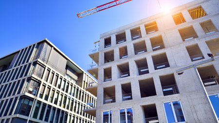 New multistory modern apartment buildings under construction in sunny day.
