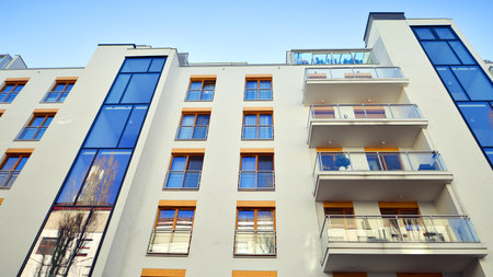 Apartment building with symmetrical modern architecture in the city. Modern apartment building on a sunny day. Facade of a modern apartment building. Bottom view.の写真素材