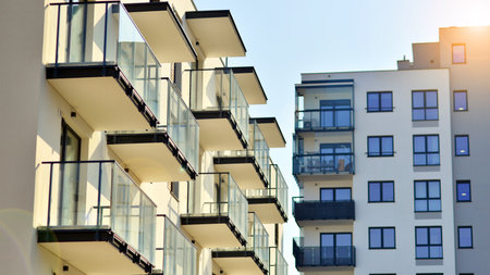Apartment building with symmetrical modern architecture in the city. Modern apartment building on a sunny day. Facade of a modern apartment building. Bottom view.の写真素材