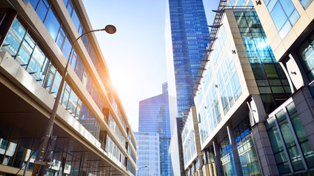 Downtown corporate business district architecture. Glass reflective office buildings against blue sky and sun light. Economy, finance, business activity concept. Rising sun on theの写真素材