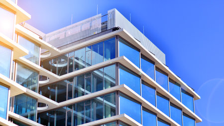 Downtown corporate business district architecture. Glass reflective office buildings against blue sky and sun light. Economy, finance, business activity concept. Rising sun on theの写真素材