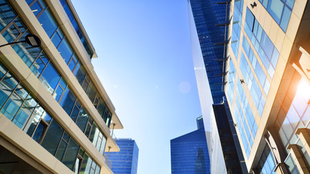 Downtown corporate business district architecture. Glass reflective office buildings against blue sky and sun light. Economy, finance, business activity concept. Rising sun on theの写真素材