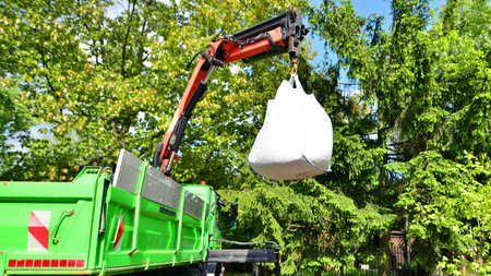 Crane with a big bag of stones. It is a white big bag with decorative stones for the property.の写真素材