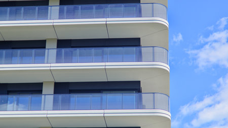 Exterior of a high modern multi-story apartment building - facade, windows and balconies. Modern glass balcony railings.の写真素材