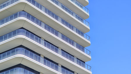 Exterior of a high modern multi-story apartment building - facade, windows and balconies. Modern glass balcony railings.の写真素材