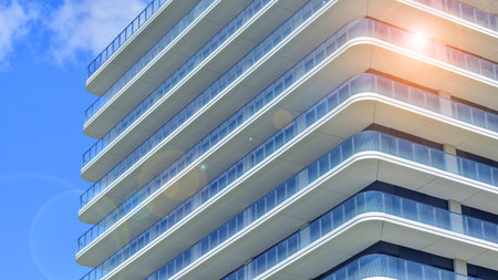 Exterior of a high modern multi-story apartment building - facade, windows and balconies. Modern glass balcony railings.の写真素材