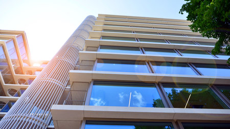 Modern office building with glass facade. Transparent glass wall of office building. Reflection of the blue sky on the facade of the building.の写真素材