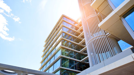Modern office building with glass facade. Transparent glass wall of office building. Reflection of the blue sky on the facade of the building.の写真素材