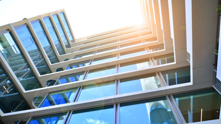 Modern office building with glass facade. Transparent glass wall of office building. Reflection of the blue sky on the facade of the building.の写真素材