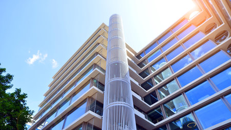 Modern office building with glass facade. Transparent glass wall of office building. Reflection of the blue sky on the facade of the building.の写真素材
