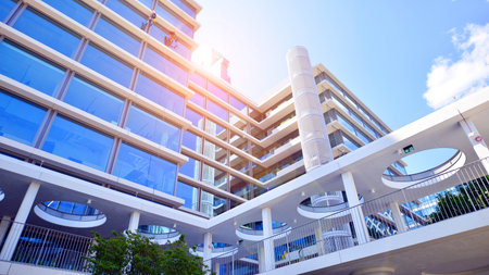Modern office building with glass facade. Transparent glass wall of office building. Reflection of the blue sky on the facade of the building.の写真素材