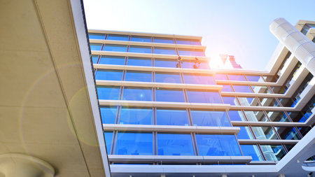 Modern office building with glass facade. Transparent glass wall of office building. Reflection of the blue sky on the facade of the building.の写真素材