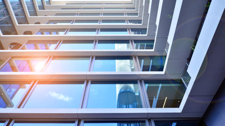 Modern office building with glass facade. Transparent glass wall of office building. Reflection of the blue sky on the facade of the building.の写真素材