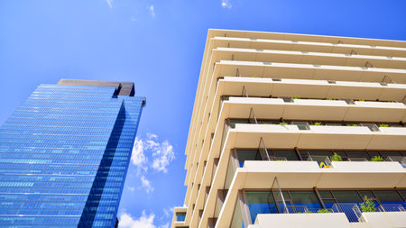 Modern office building with glass facade. Transparent glass wall of office building. Reflection of the blue sky on the facade of the building.の写真素材