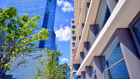 City life, urban landscape and ecology. Modern office complex with glass facades and smooth lines against backdrop of green trees, concept of modern architecture. Organically builtの写真素材