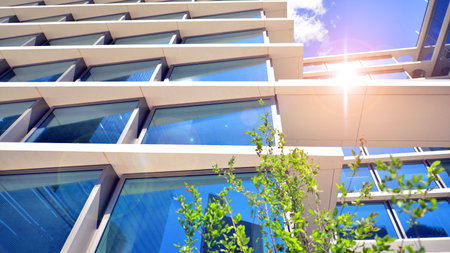 City life, urban landscape and ecology. Modern office complex with glass facades and smooth lines against backdrop of green trees, concept of modern architecture. Organically builtの写真素材