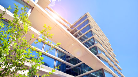 City life, urban landscape and ecology. Modern office complex with glass facades and smooth lines against backdrop of green trees, concept of modern architecture. Organically builtの写真素材