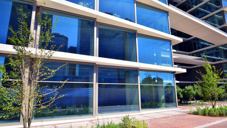 City life, urban landscape and ecology. Modern office complex with glass facades and smooth lines against backdrop of green trees, concept of modern architecture. Organically builtの写真素材