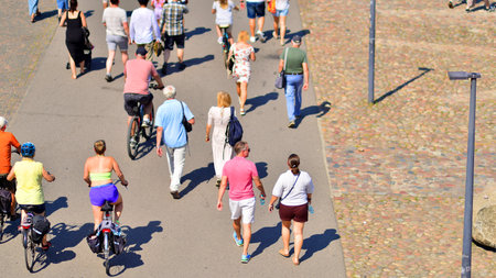 Warsaw, Poland. 15 August 2025. Tourists and residents crossing promenade along the Vistula river crowded. Groups of people walking together crossing a promenade on a weekend day.のeditorial素材