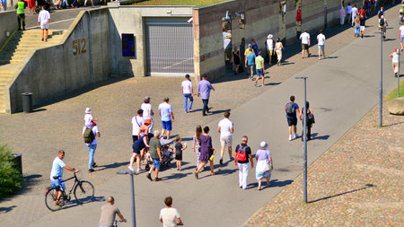 Warsaw, Poland. 15 August 2025. Tourists and residents crossing promenade along the Vistula river crowded. Groups of people walking together crossing a promenade on a weekend day.のeditorial素材