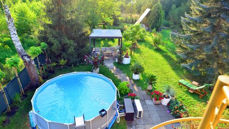 Garden of a suburban house in summer in which you can see a removable swimming pool, pergola in a place with a lot of vegetation.の写真素材
