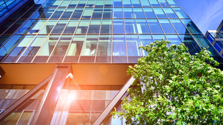 Glass office building surrounded with green trees. Eco-friendly office building. Sustainable...