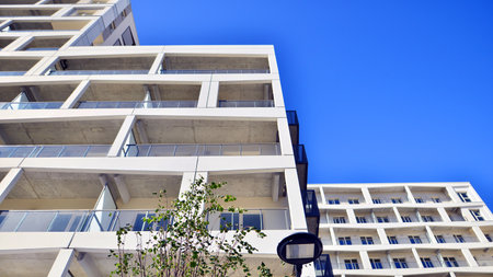 A residential building by lush green trees and surrounded by fresh vegetation on a clear sunny day....