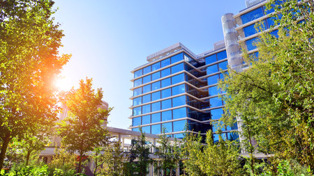 Glass office building surrounded with green trees. Eco-friendly office building. Sustainable...