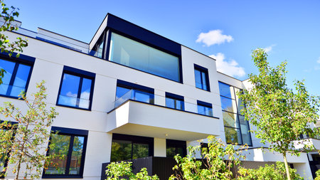 Modern apartment building with balconies and greenery. The structure features a glass wall and lush...