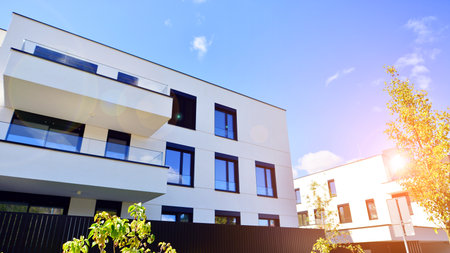 Modern apartment building with balconies and greenery. The structure features a glass wall and lush...
