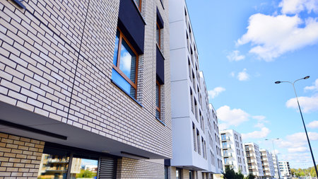 A residential building by lush green trees and surrounded by fresh vegetation on a clear sunny day....