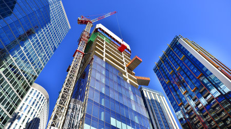 Crane on the construction site in a site surrounded by the high buildings. Office building under...