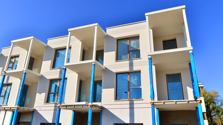 New multistory modern apartment buildings under construction in sunny day.