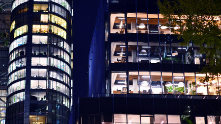 Modern office building in city center illuminated at night. Rows of lit windows against the architectural grid of a modern facade. Concrete and glass facade in its night version.の写真素材
