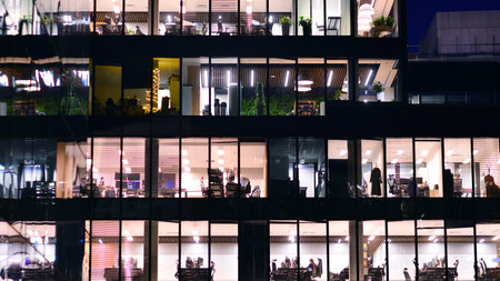 Modern office building in city center illuminated at night. Rows of lit windows against the architectural grid of a modern facade. Concrete and glass facade in its night version.の写真素材