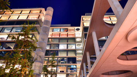 Modern office building in city center illuminated at night. Rows of lit windows against the architectural grid of a modern facade. Concrete and glass facade in its night version.の写真素材