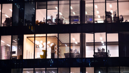 Modern office building in city center illuminated at night. Rows of lit windows against the architectural grid of a modern facade. Concrete and glass facade in its night version.の写真素材