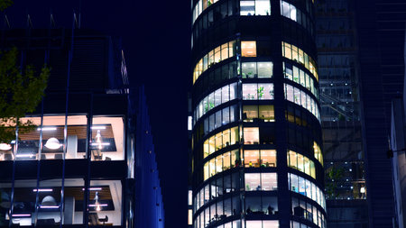 Modern office building in city center illuminated at night. Rows of lit windows against the architectural grid of a modern facade. Concrete and glass facade in its night version.の写真素材