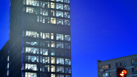 Modern office building in city center illuminated at night. Rows of lit windows against the architectural grid of a modern facade. Concrete and glass facade in its night version.の写真素材