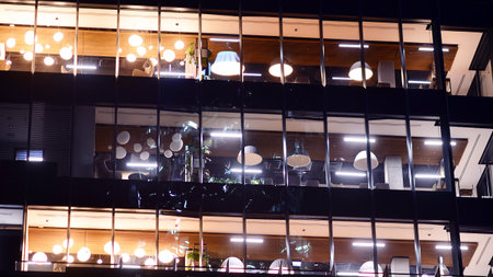 Modern office building in city center illuminated at night. Rows of lit windows against the architectural grid of a modern facade. Concrete and glass facade in its night version.の写真素材
