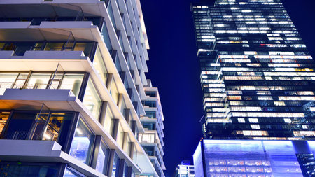 Modern office building in city center illuminated at night. Rows of lit windows against the...