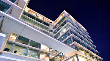Modern office building in city center illuminated at night. Rows of lit windows against the...