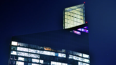 Modern office building in city center illuminated at night. Rows of lit windows against the architectural grid of a modern facade. Concrete and glass facade in its night version.の写真素材