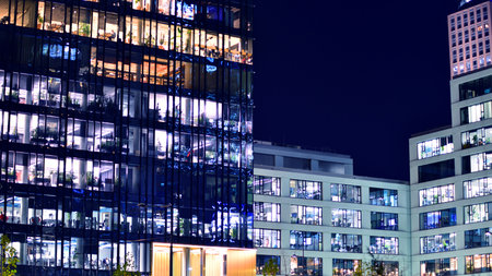 Modern office building in city center illuminated at night. Rows of lit windows against the architectural grid of a modern facade. Concrete and glass facade in its night version.の写真素材