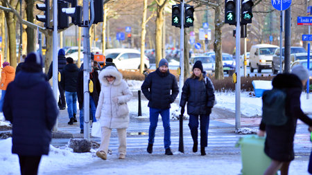 Warsaw, Poland. 5 January 2026. Pedestrians cross the road at a pedestrian crossing in winter. In the background, the city, buildings, cars.のeditorial素材
