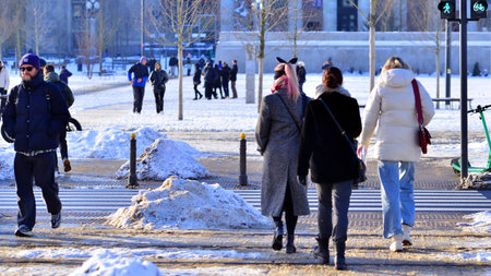 Warsaw, Poland. 5 January 2026. Pedestrians cross the road at a pedestrian crossing in winter. In the background, the city, buildings, cars.のeditorial素材