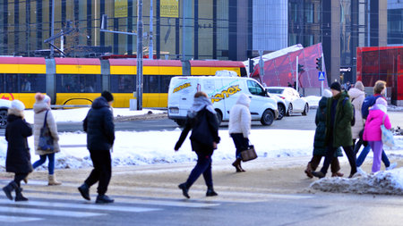 Warsaw, Poland. 5 January 2026. Pedestrians cross the road at a pedestrian crossing in winter. In the background, the city, buildings, cars.のeditorial素材