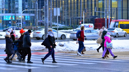 Warsaw, Poland. 5 January 2026. Pedestrians cross the road at a pedestrian crossing in winter. In the background, the city, buildings, cars.のeditorial素材